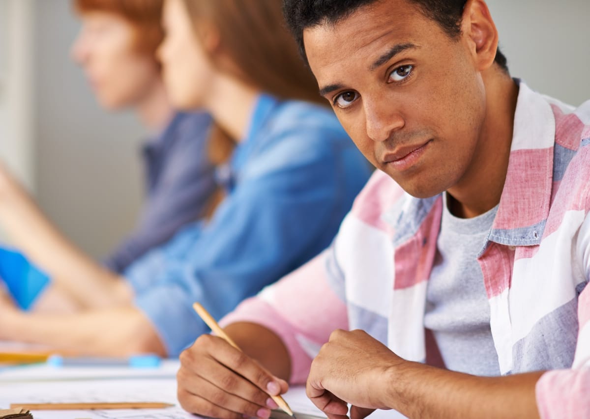 Estudante resolvendo exercícios com lápis sobre o caderno