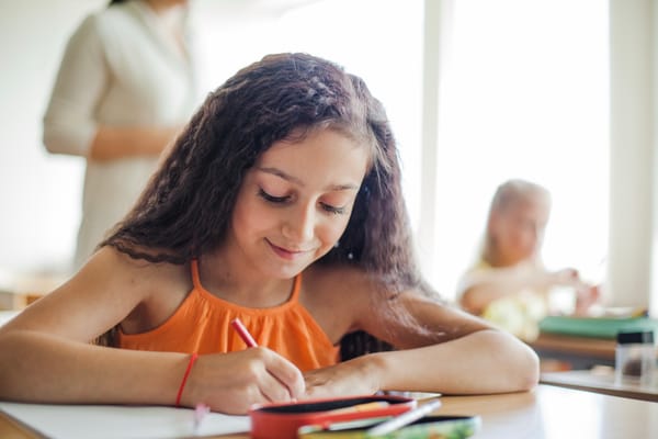 Estudante sentada à carteira segurando um lápis
