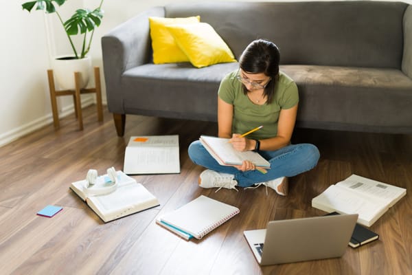 Jovem estudando com livros em casa para as provas